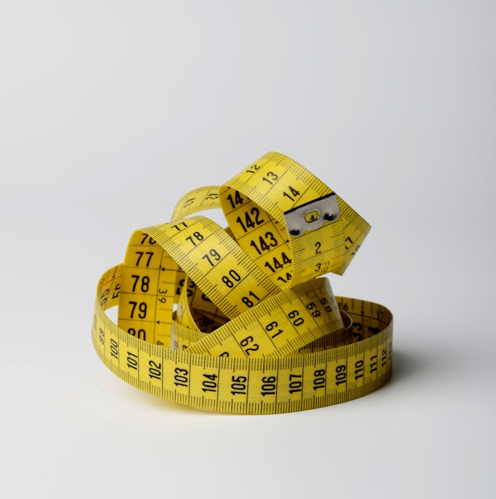 The Art of Drawing Readers In: Your attractive post title goes here A bright yellow measuring tape coiled in loops, showcasing measurements clearly against a white background.