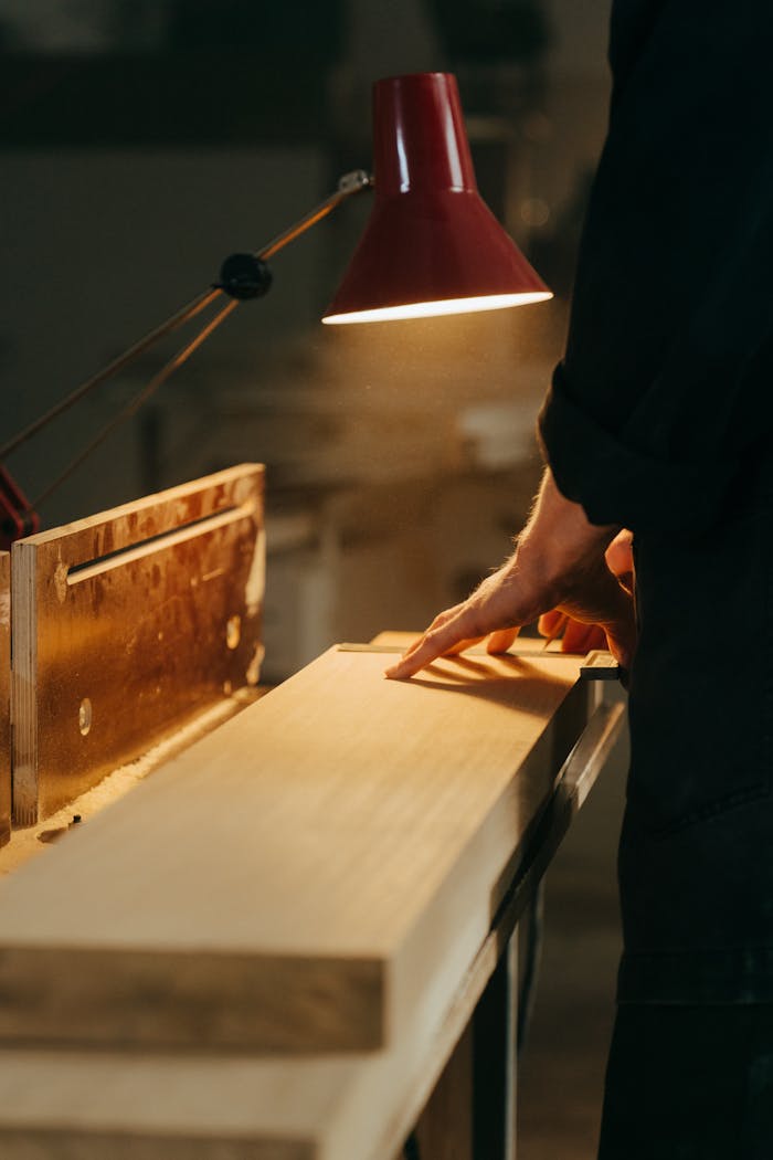 team-03 A skilled craftsman handcrafting wood under warm light in a workshop, focusing on precision.